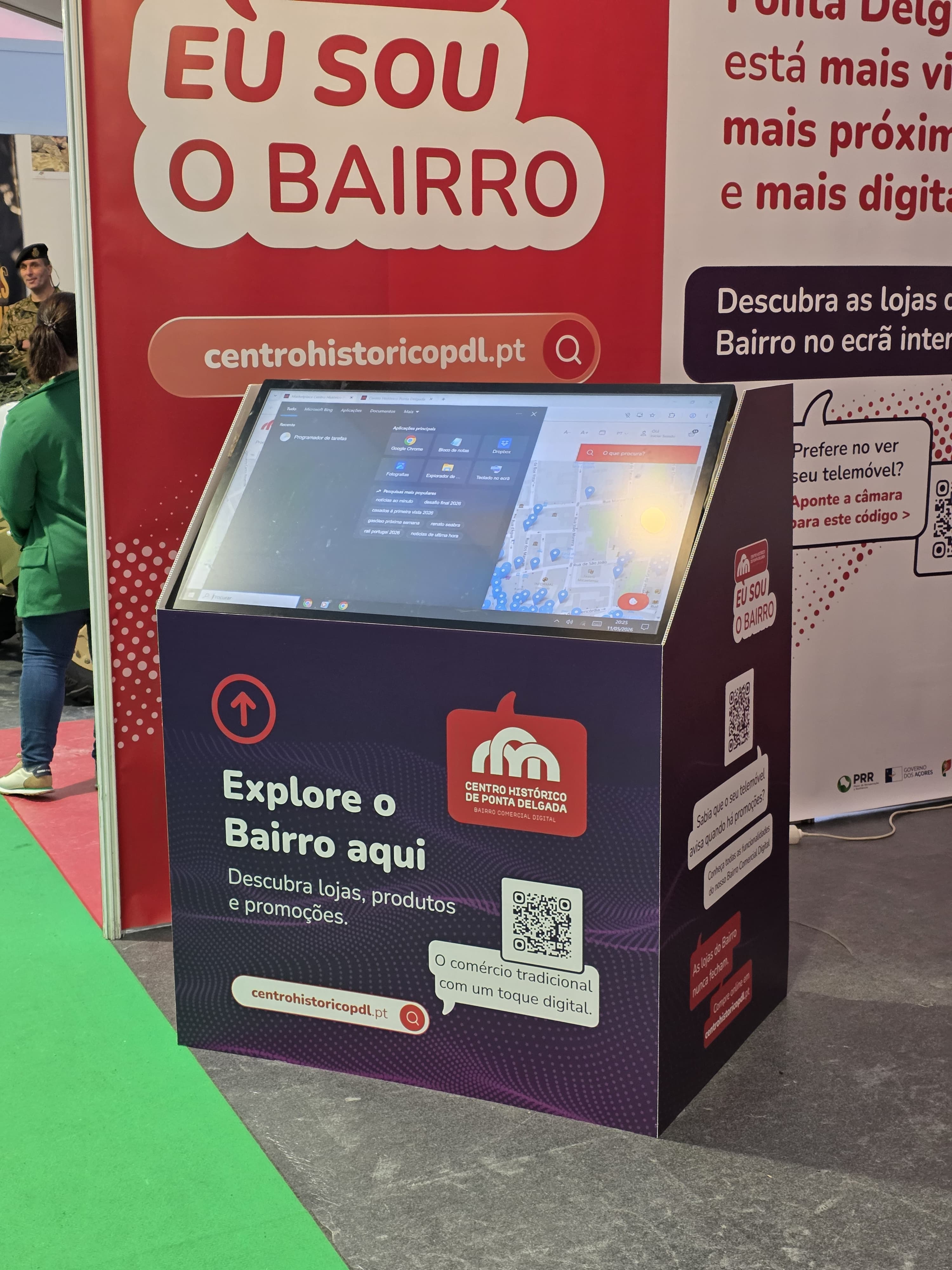 Stand do Bairro Comercial Digital na FICSA 2026 com visitantes a interagir com os painéis